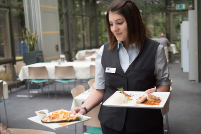 Junge Frau, die im Restaurant des Bildungszentrums Essen serviert