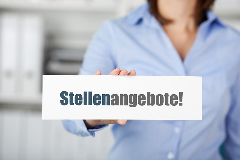 Eine Frau hält ein Schild mit dem Schriftzug "Stellenangebote"