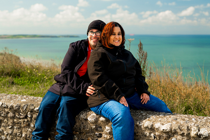 Das Foto zeigt Alina und Tim auf einer Deichmauer sitzend, im Hintergrund das Meer