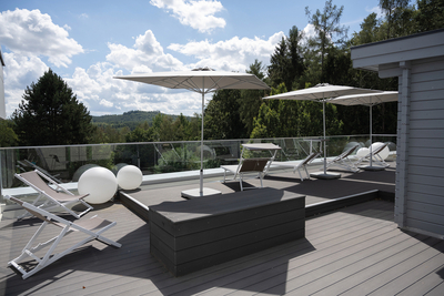 Dachterrasse des Bildungszentrums mit kugelförmigen Bodenlampen, großen weißen Sonnenschirmen und zahlreichen Liegestühlen