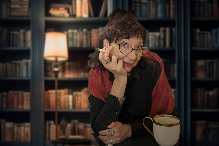 Porträt von Thea Loth vor einem Bücherregal mit Zigarette in der Hand 