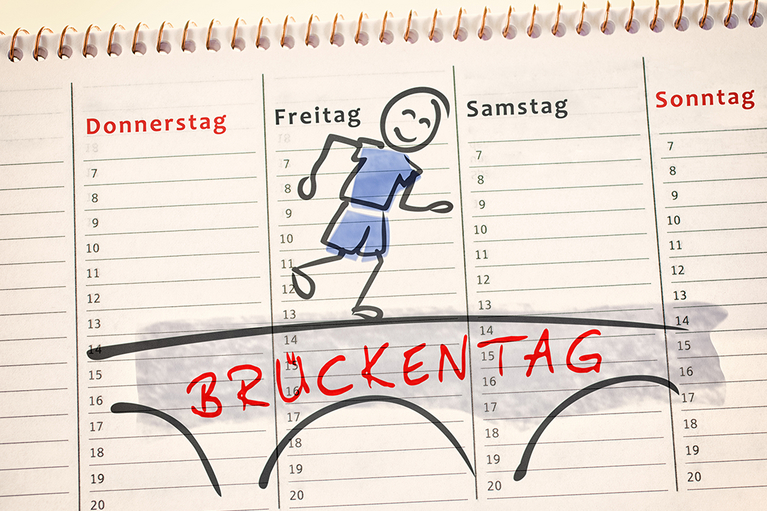 Kalender über den der Schriftzug Brückentage steht, über den ein Cartoon-Männchen läuft