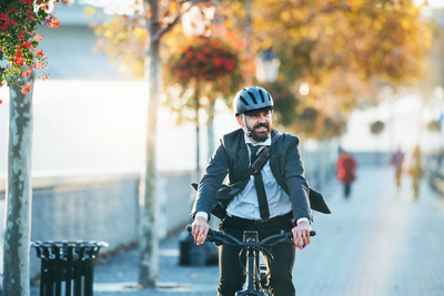 Mann mit Helm auf Fahrrad in einer Straße mit herbstlichen Bäumen