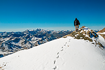 Mann steigt einen Berg hinauf, Füße im Schnee